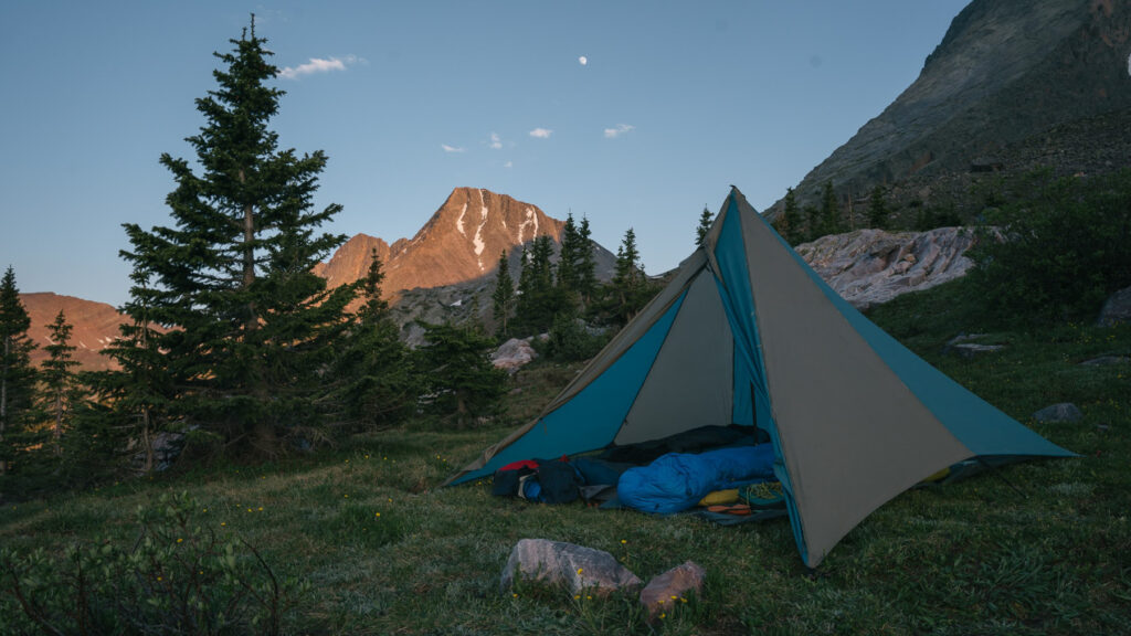 Solo camping tent at sunset in the mountains